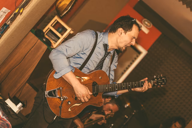 Gitarist svira crvenu polušuplju gitaru, snimljeno odozgo