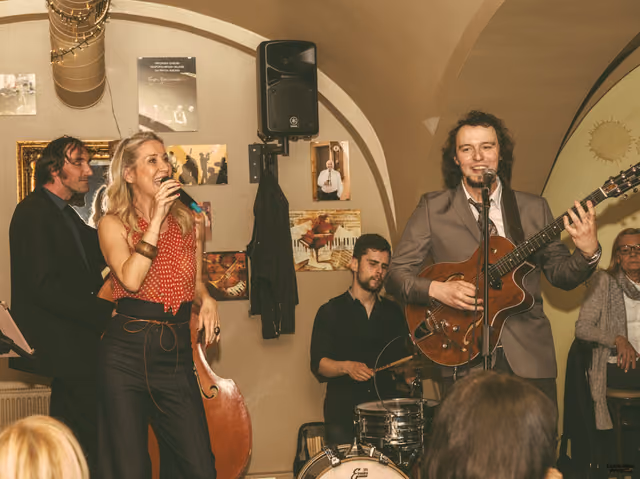 Bend svira u svođenoj birtiji, pjevačica i gitarist uz mikrofone