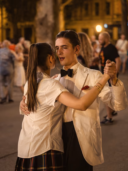 Par pleše na večernjem plesu u parku, on u bijelom sakou